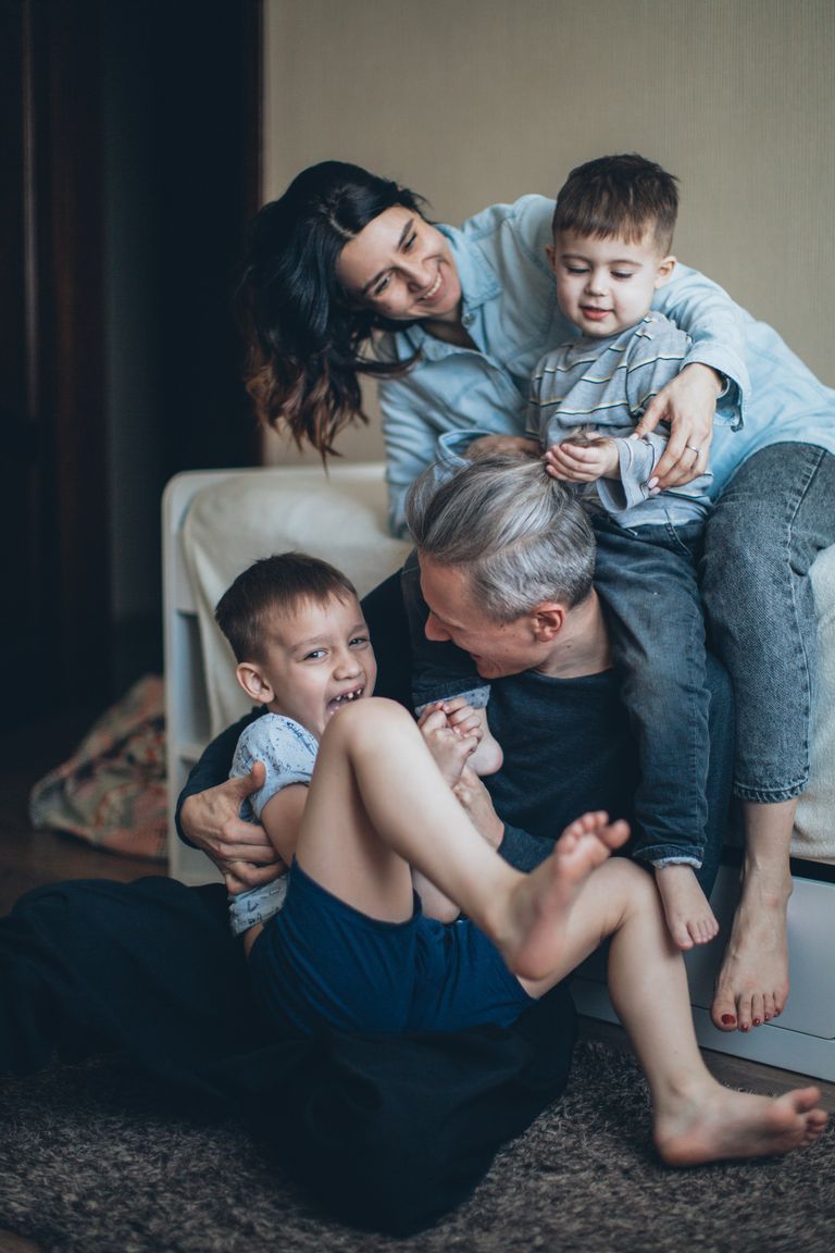 Joyful family of four playing affectionately together indoors, sharing a bonding moment.