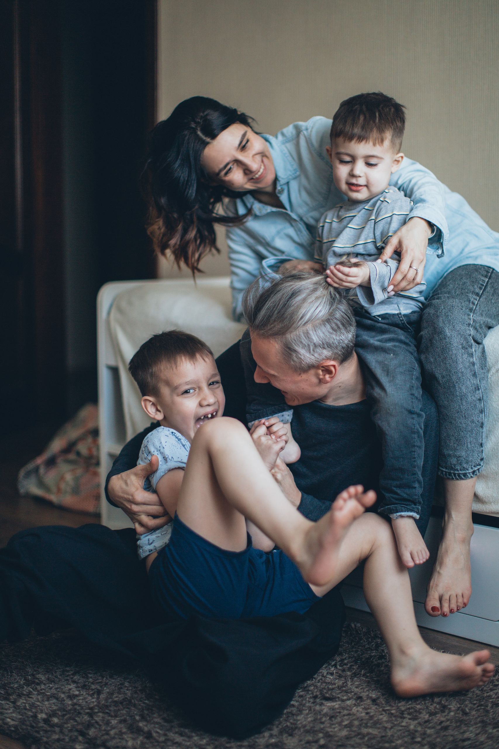 Joyful family of four playing affectionately together indoors, sharing a bonding moment.