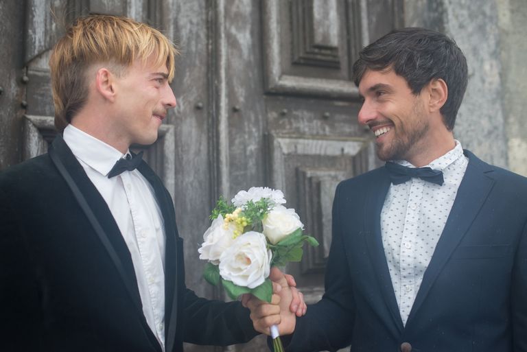 Joyful image of a gay couple celebrating their wedding day outdoors in Portugal.