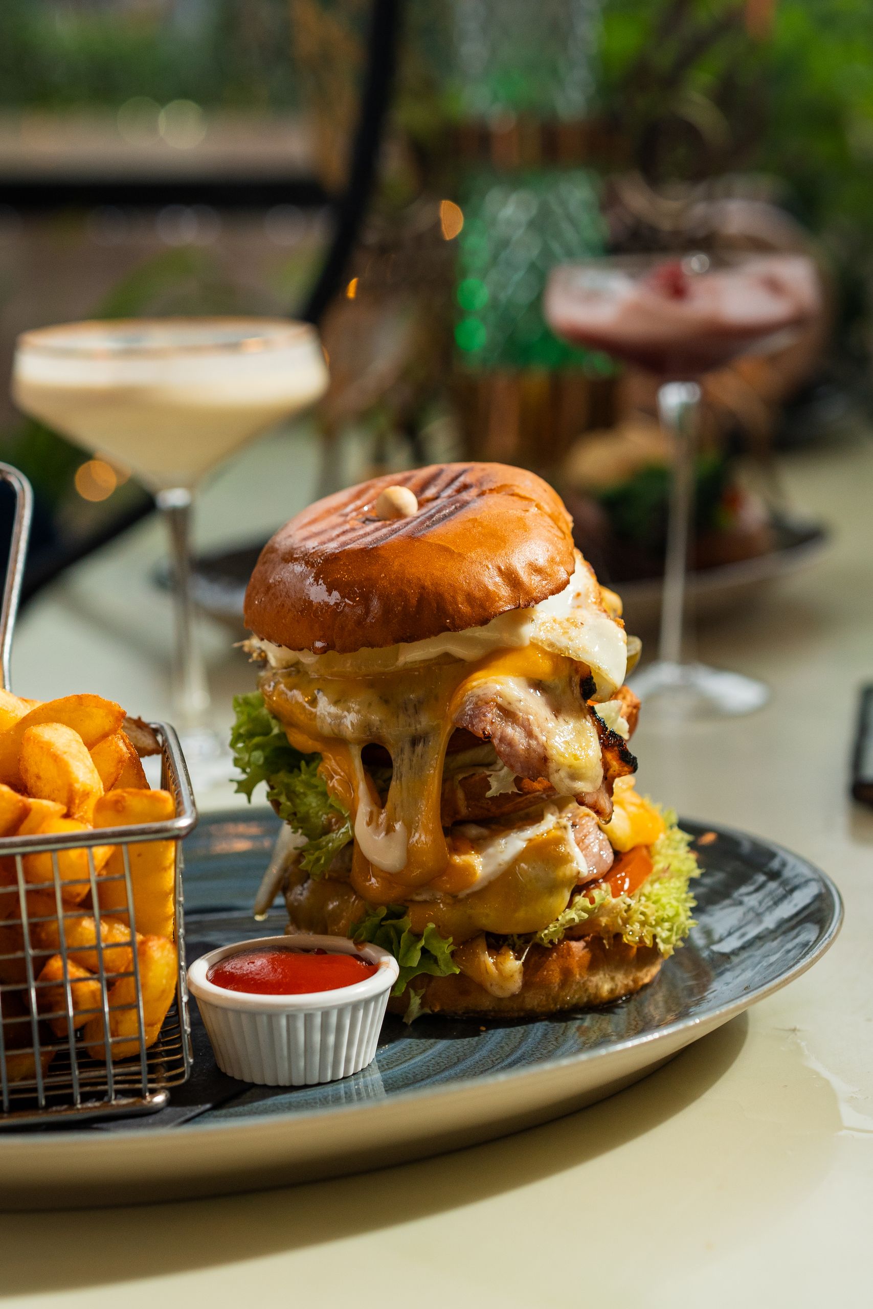 Juicy cheeseburger with fries, ketchup, and cocktails on a table in England.