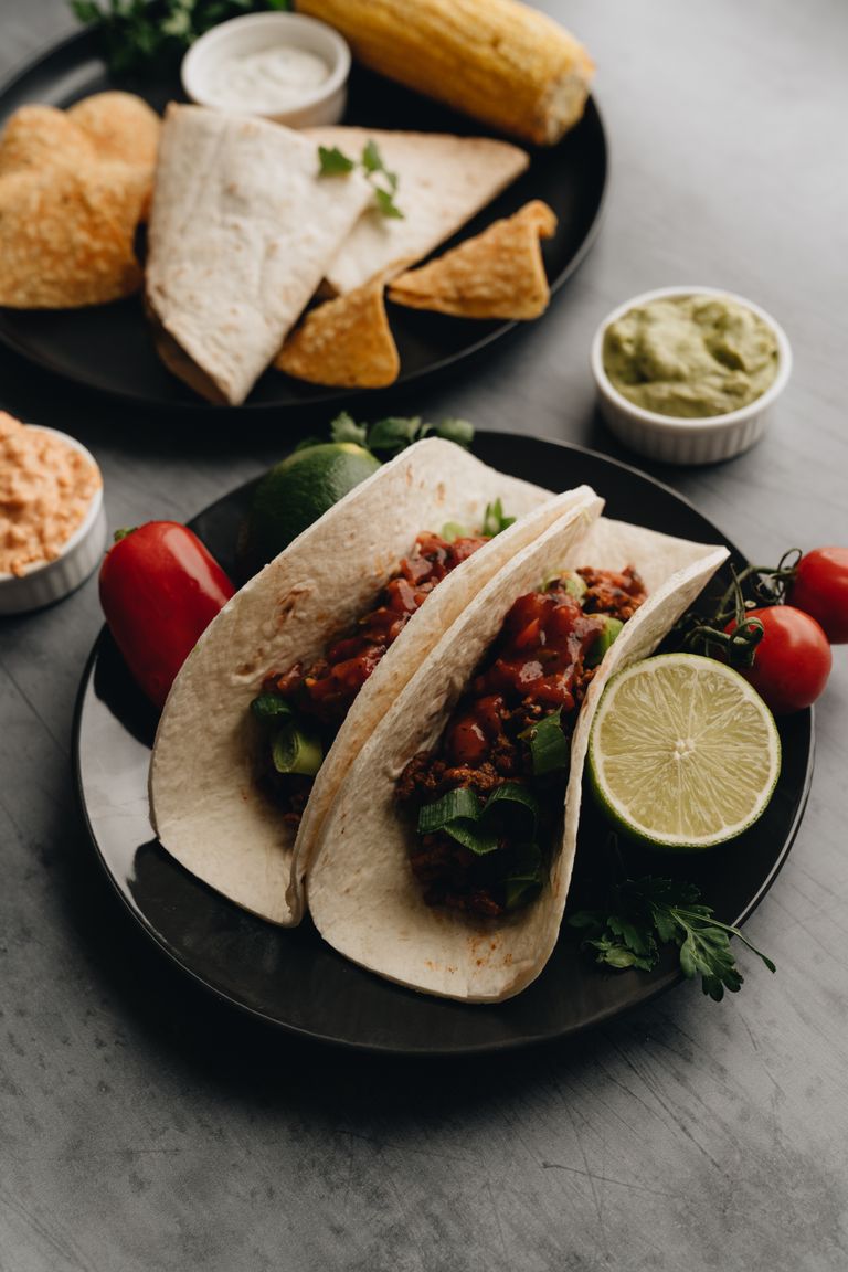 Mouthwatering tacos filled with vegetables and meat, served with lime and guacamole.