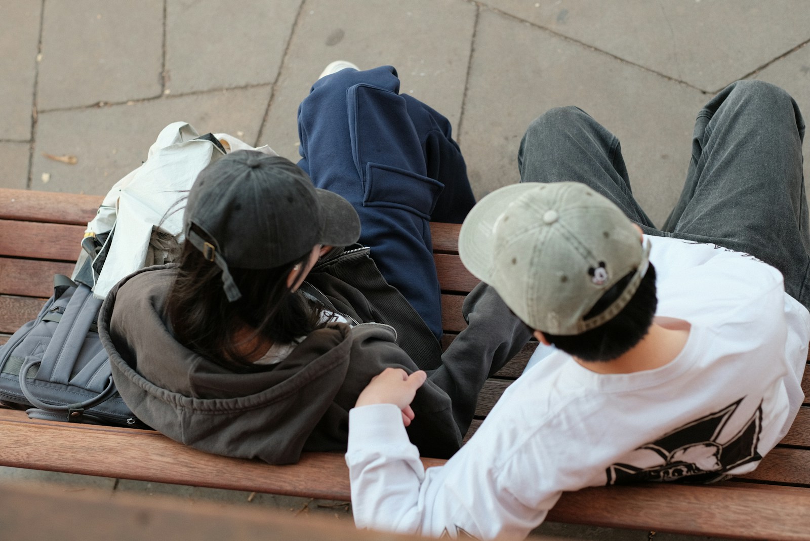 A group of people sitting on top of a wooden bench