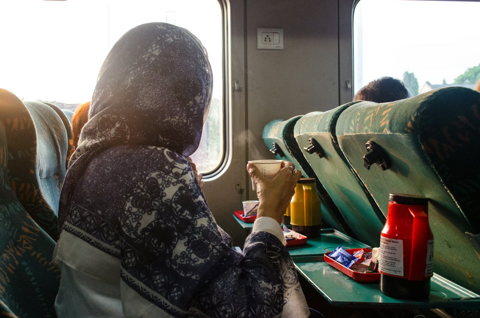 a person sitting at a table with a drink and a window