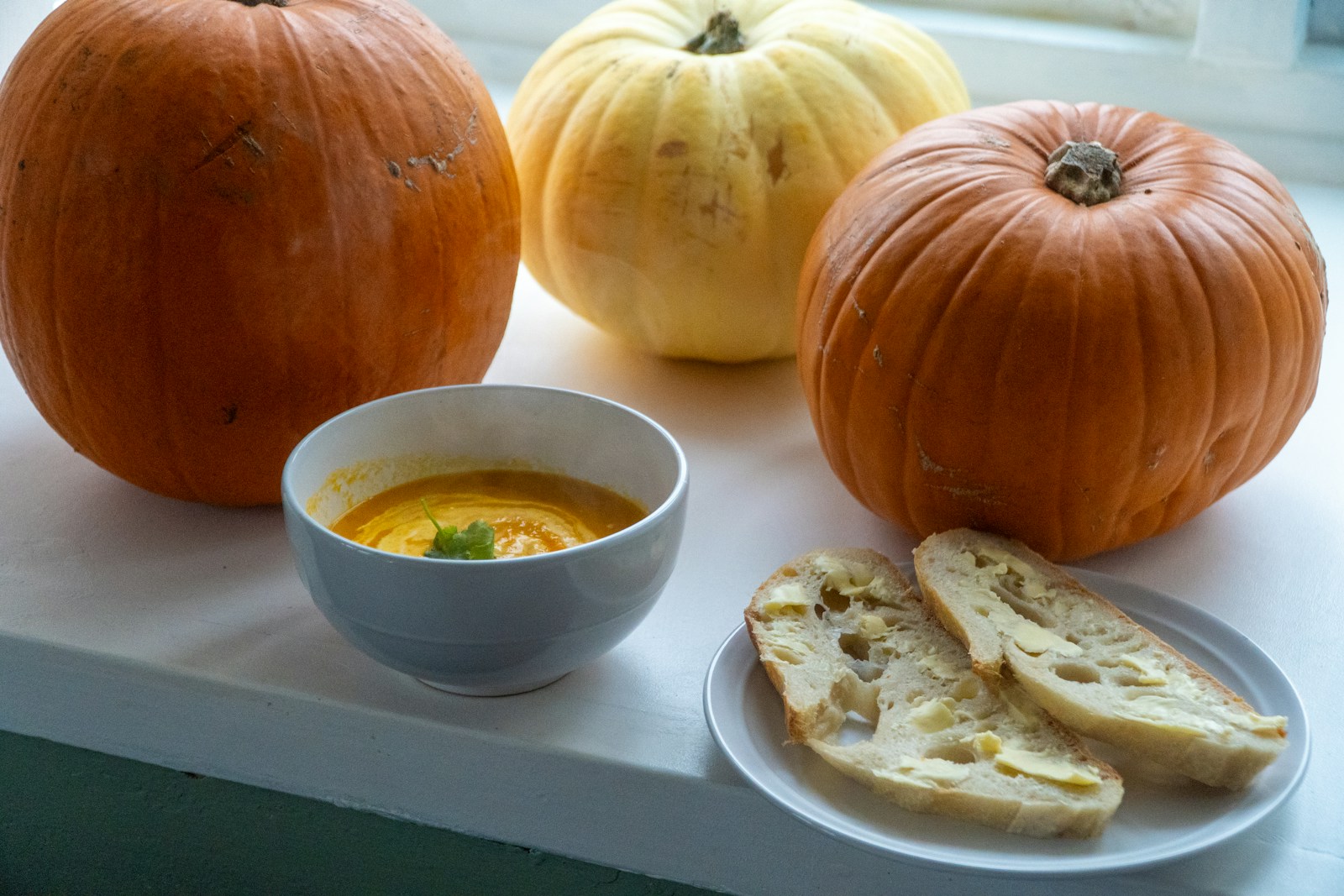 Pumpkins, soup, and bread on a windowsill
