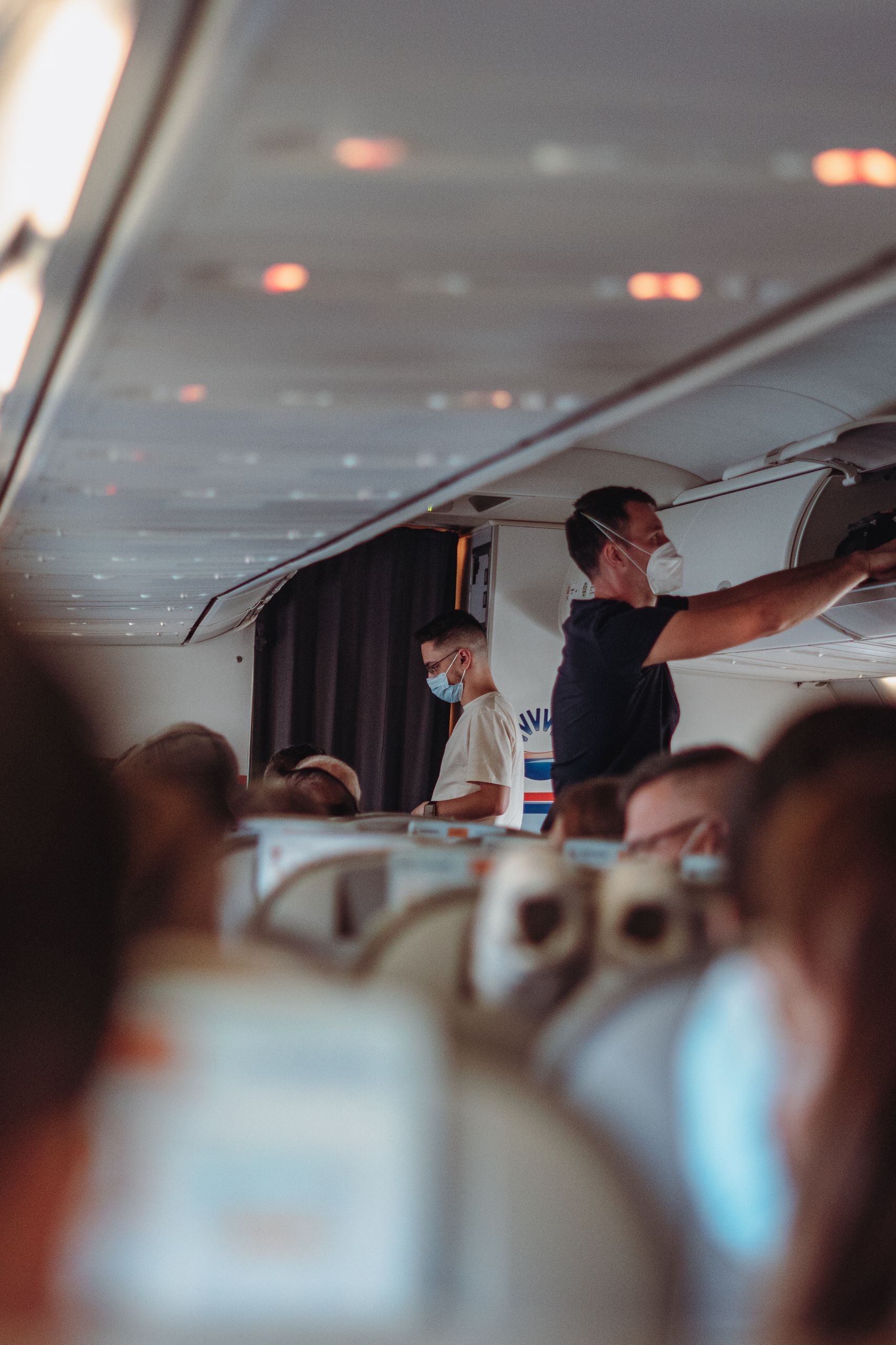 Passengers on an airplane wearing face masks, emphasizing travel safety and health protocols.