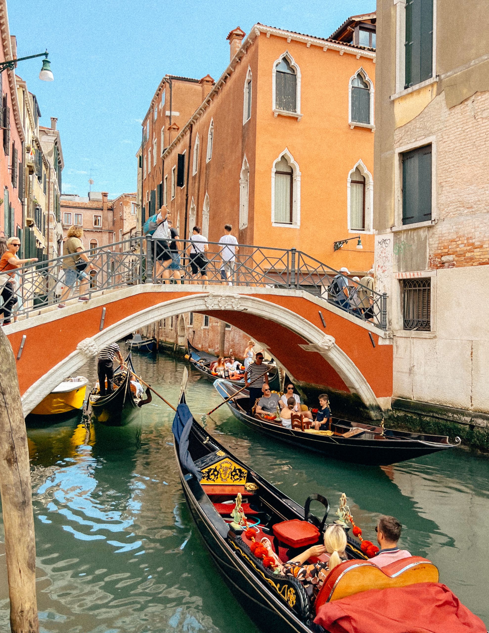Picturesque scene of gondolas navigating a historic canal under a bridge in Venice.