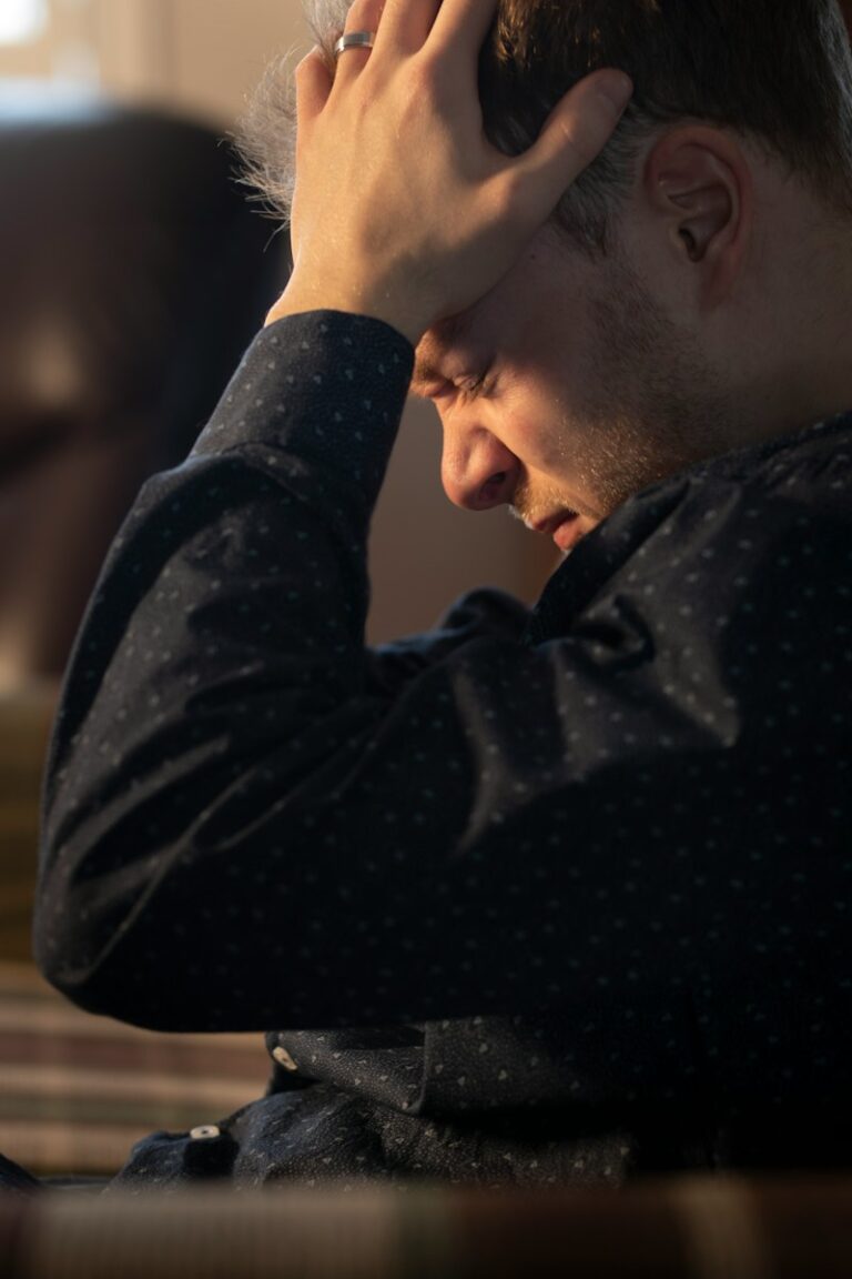 a man sitting at a table with his hand on his head