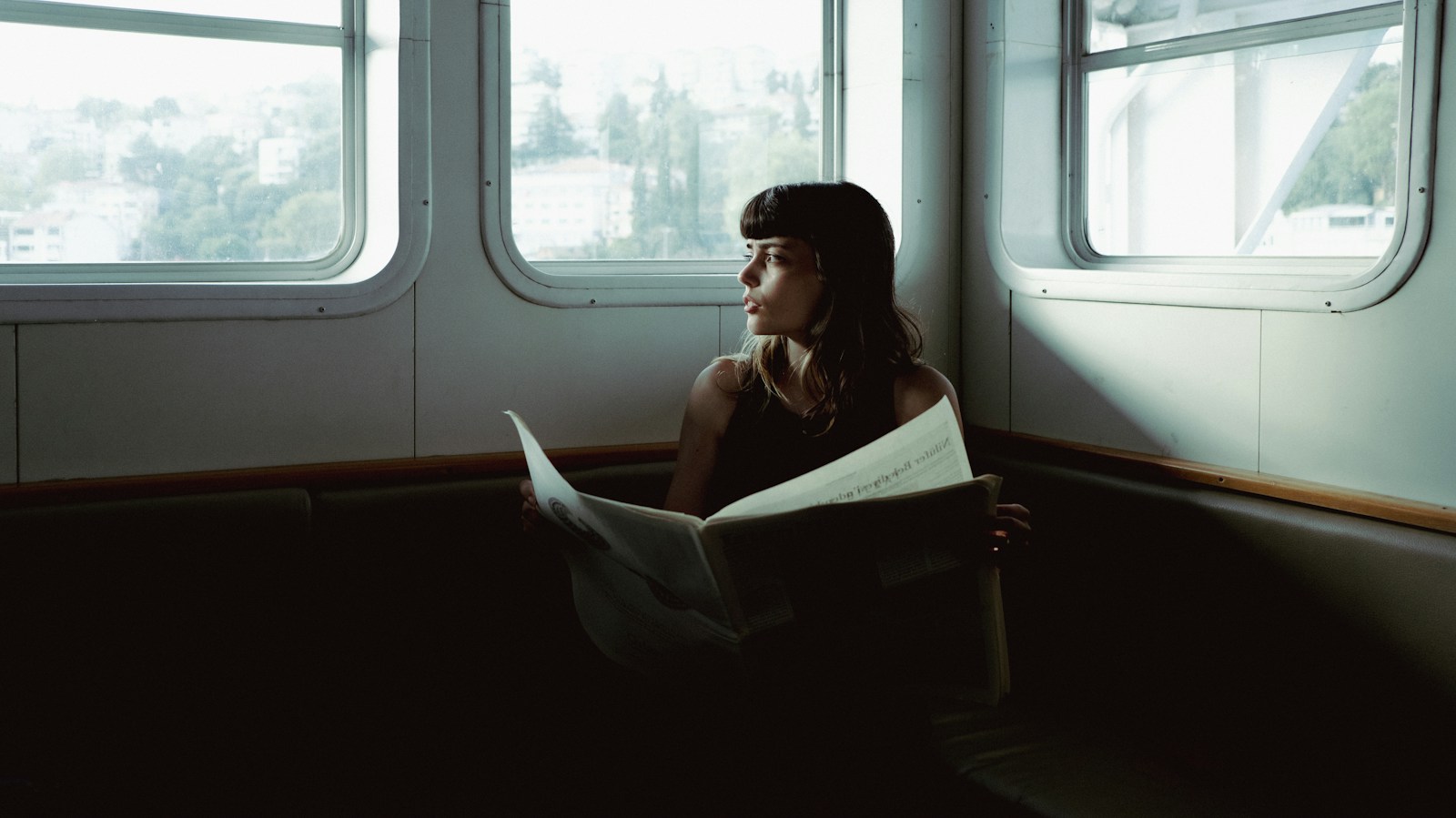 A woman sitting on a boat reading a paper