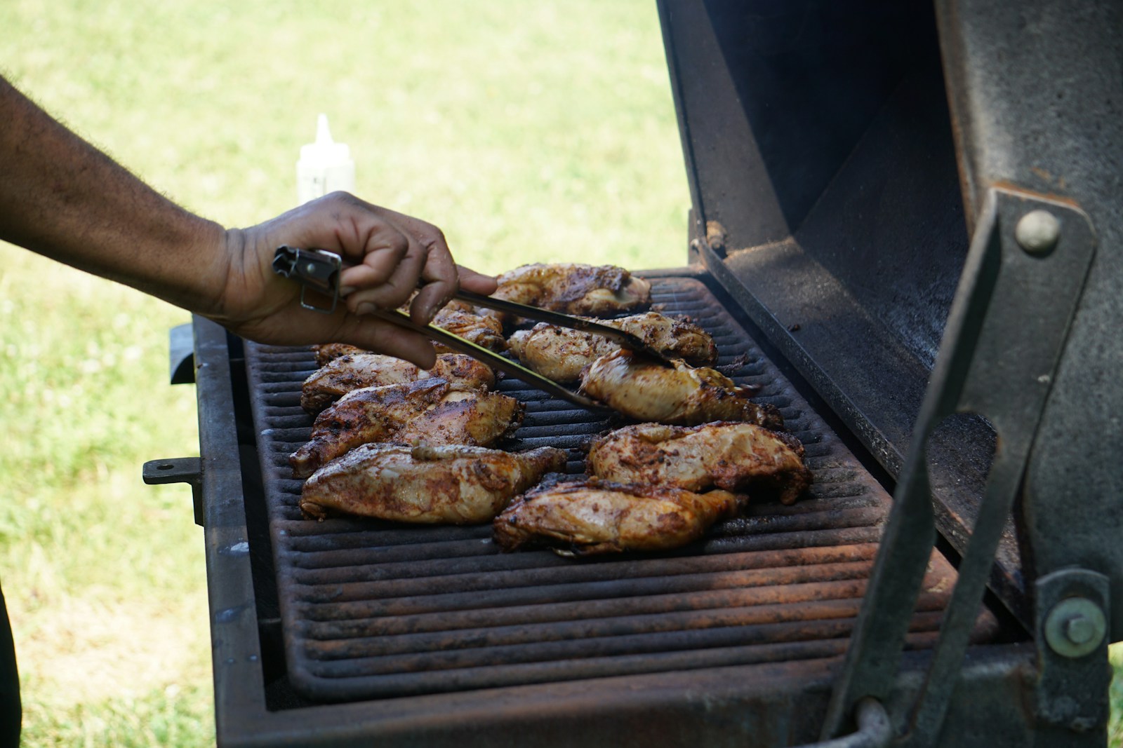 a person is cooking chicken on a grill