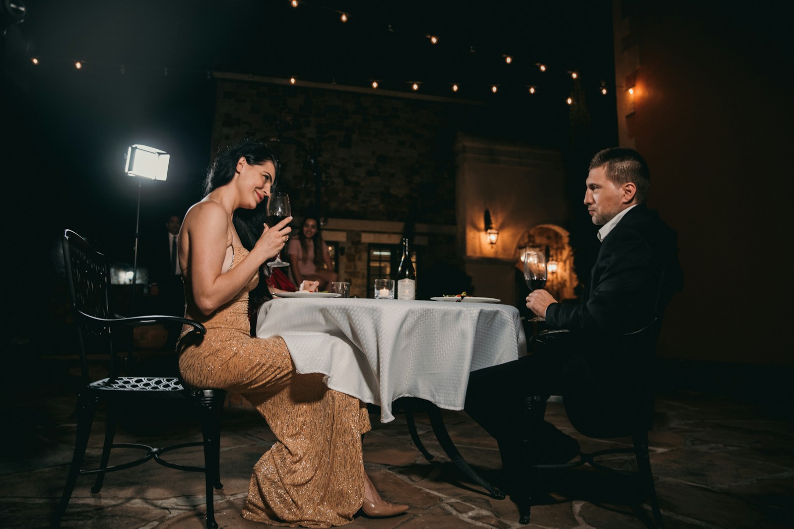 man sitting in front of woman holding wine glass