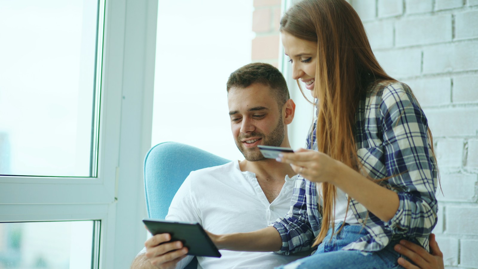 Couple happily shopping online with tablet and credit card