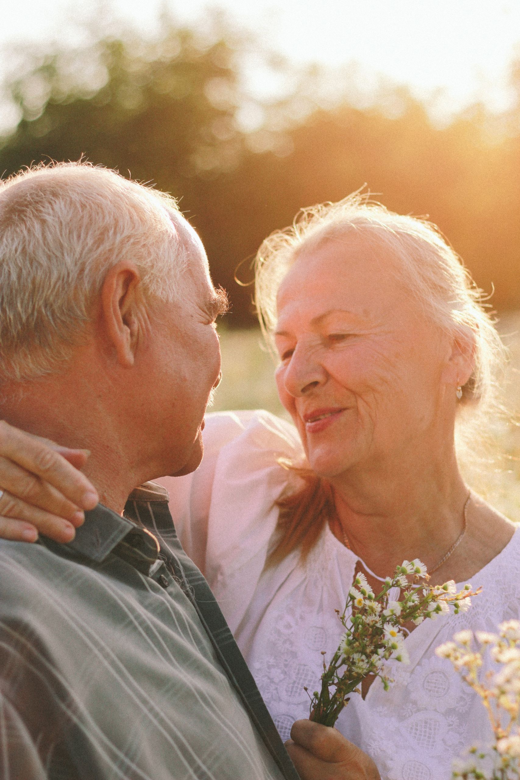 Senior couple sharing a loving moment outdoors during sunset.
