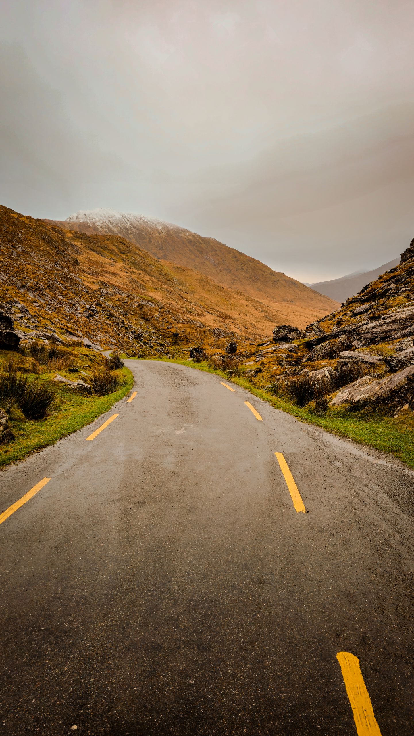 Serene mountain road in Killarney, Ireland, surrounded by rugged landscape and misty hills.