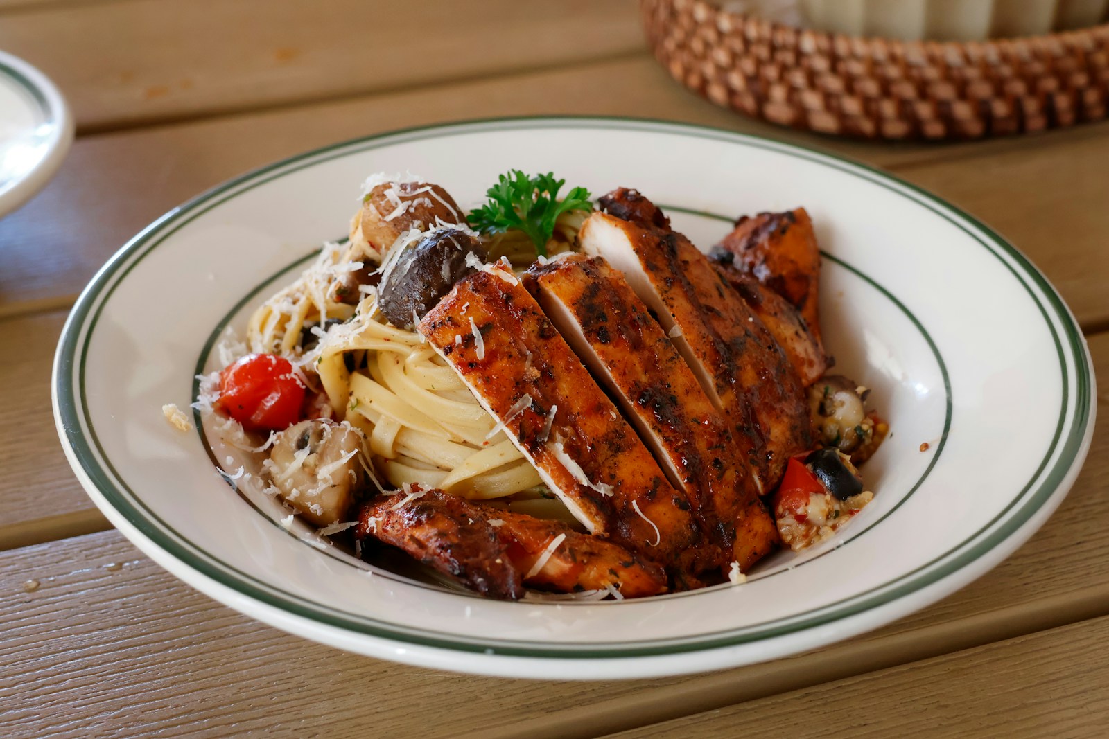 Sliced grilled chicken breast over pasta with vegetables