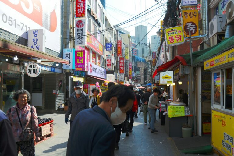 A group of people walking down a street next to stores