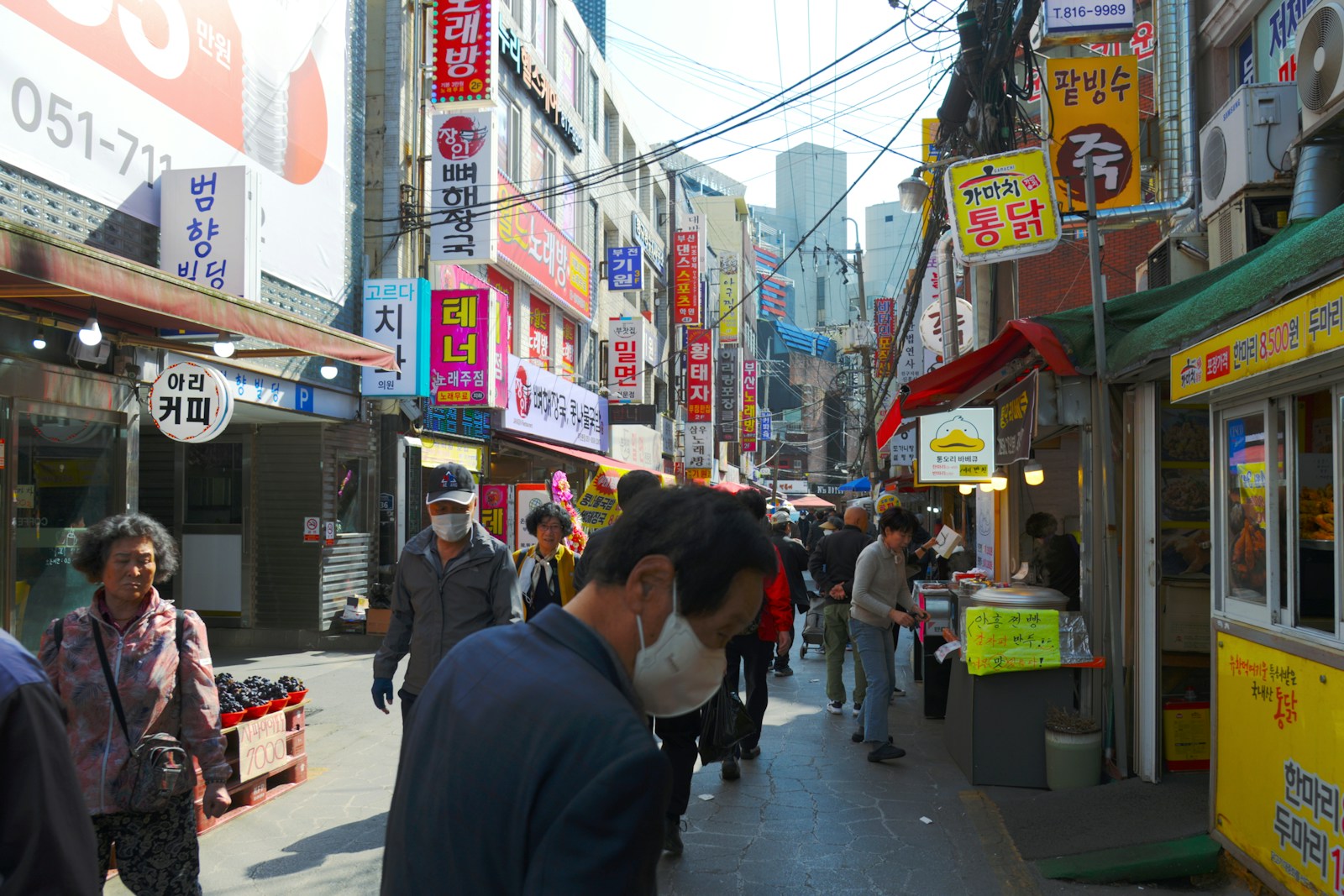 A group of people walking down a street next to stores