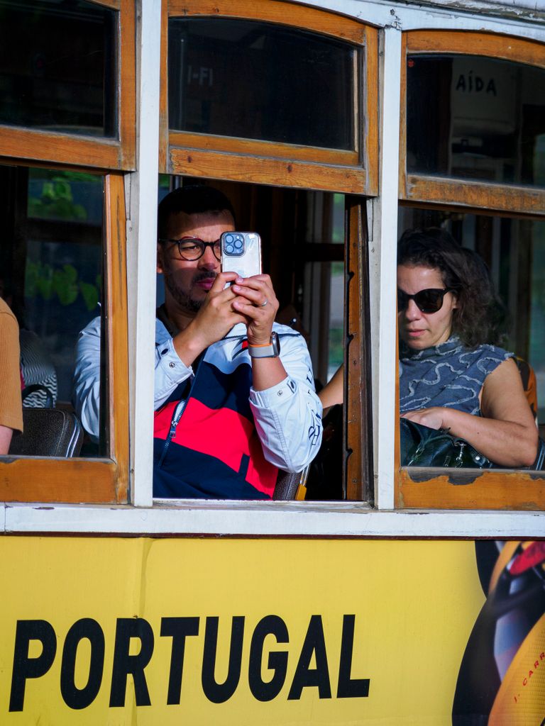 Tourists capturing moments on a tram ride in Portugal, highlighting travel and exploration.