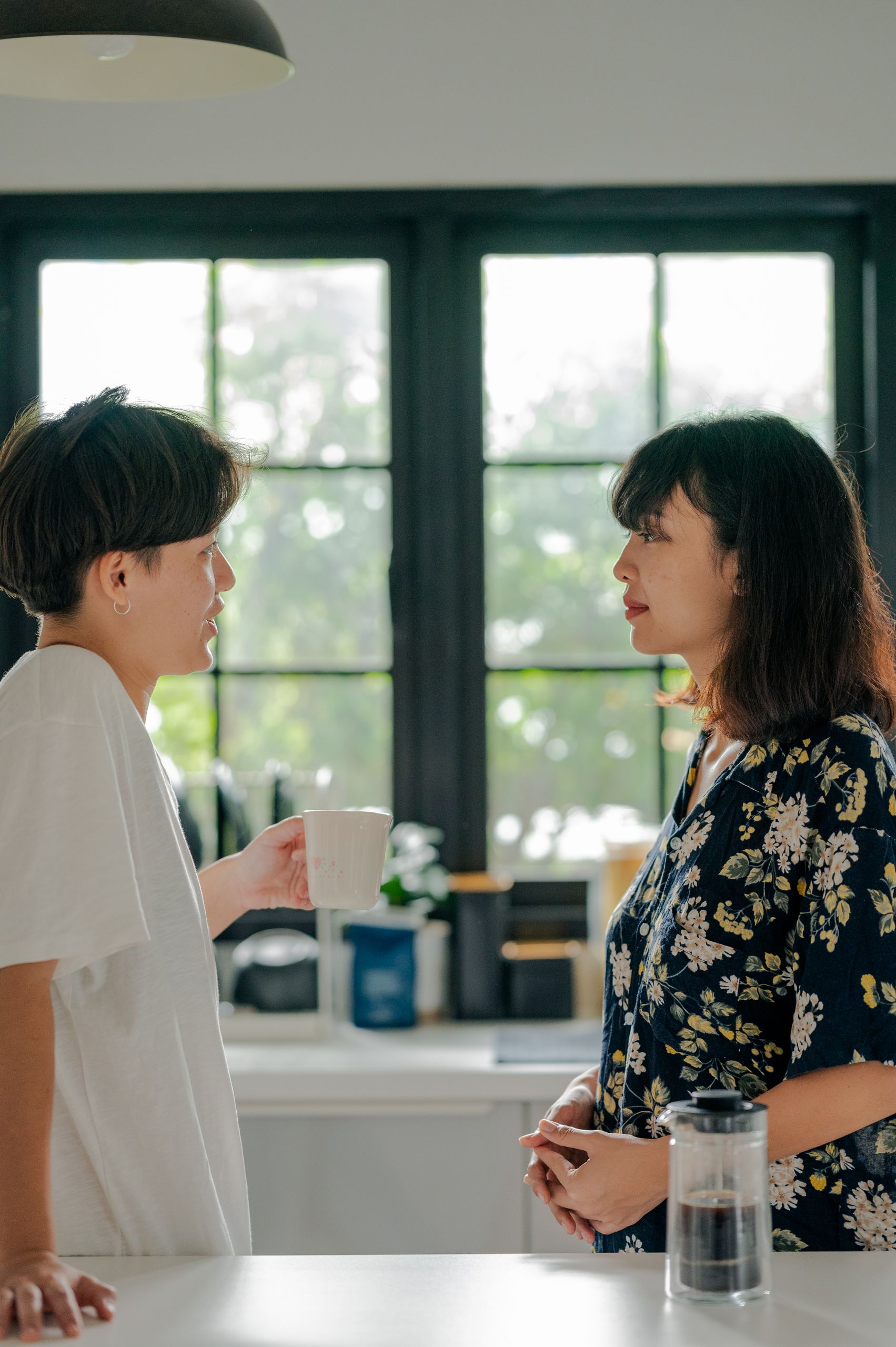 Two adults chatting over coffee in a cozy kitchen setting, capturing a warm morning moment.