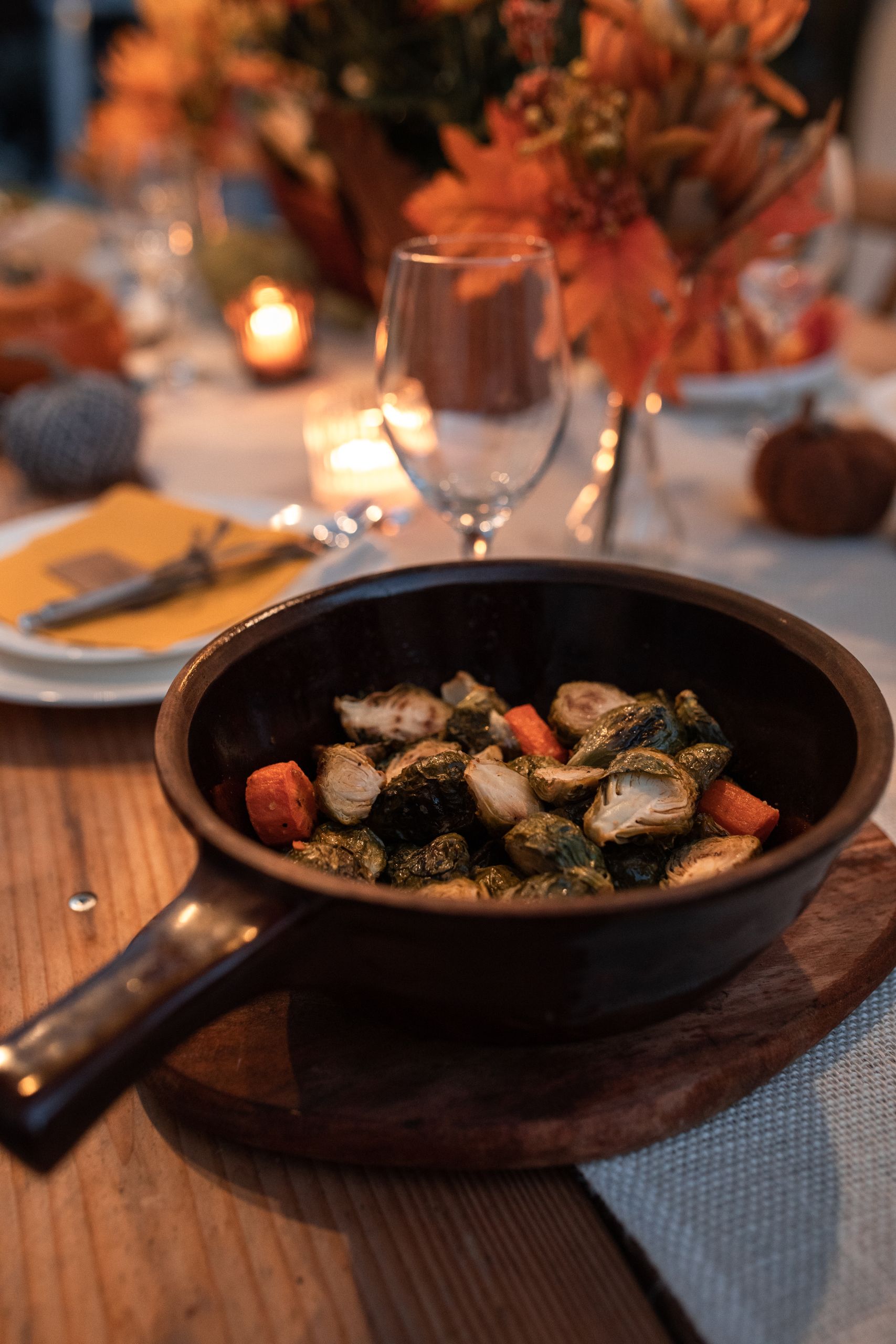 Warm fall-themed table setting with roasted vegetables in a pan, perfect for Thanksgiving dinner inspiration.