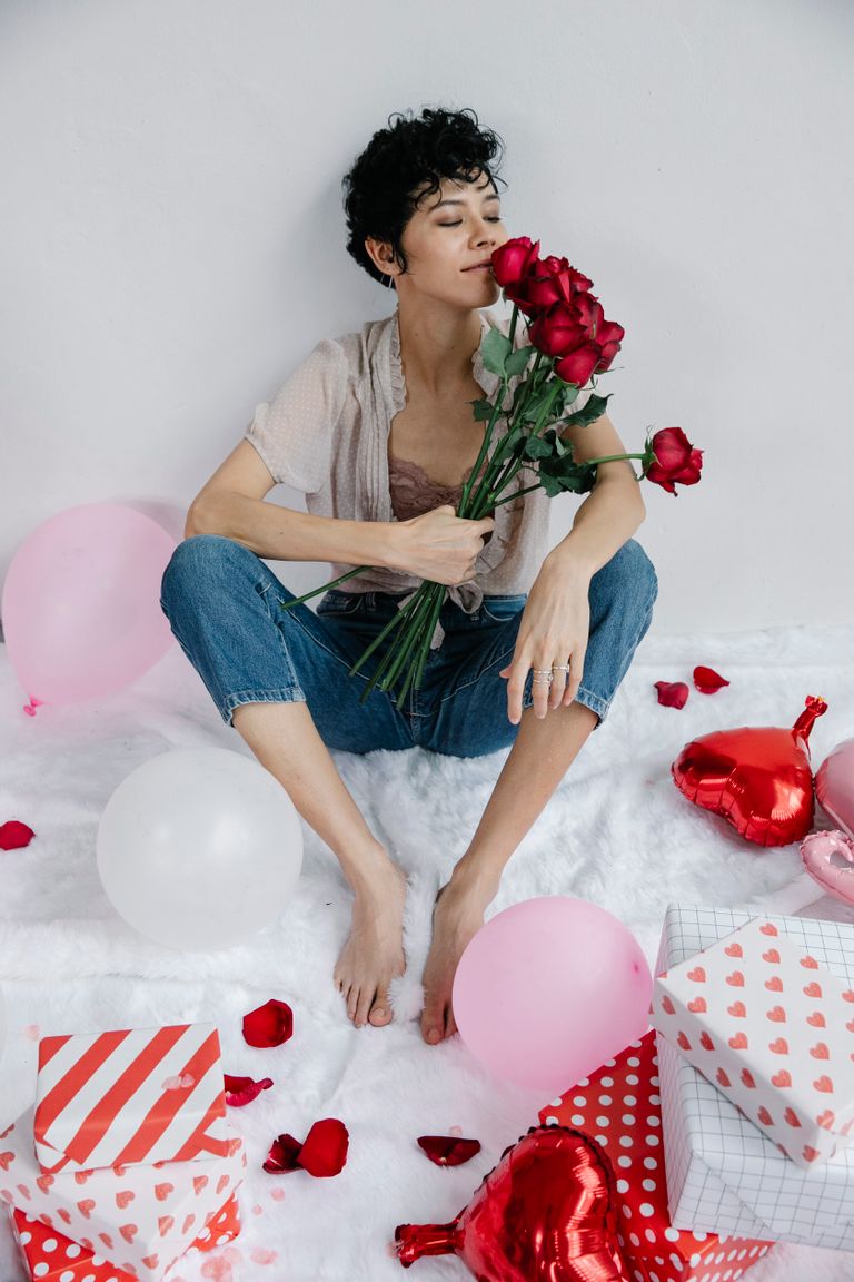 Woman enjoying Valentine's Day with roses, balloons, and gifts.