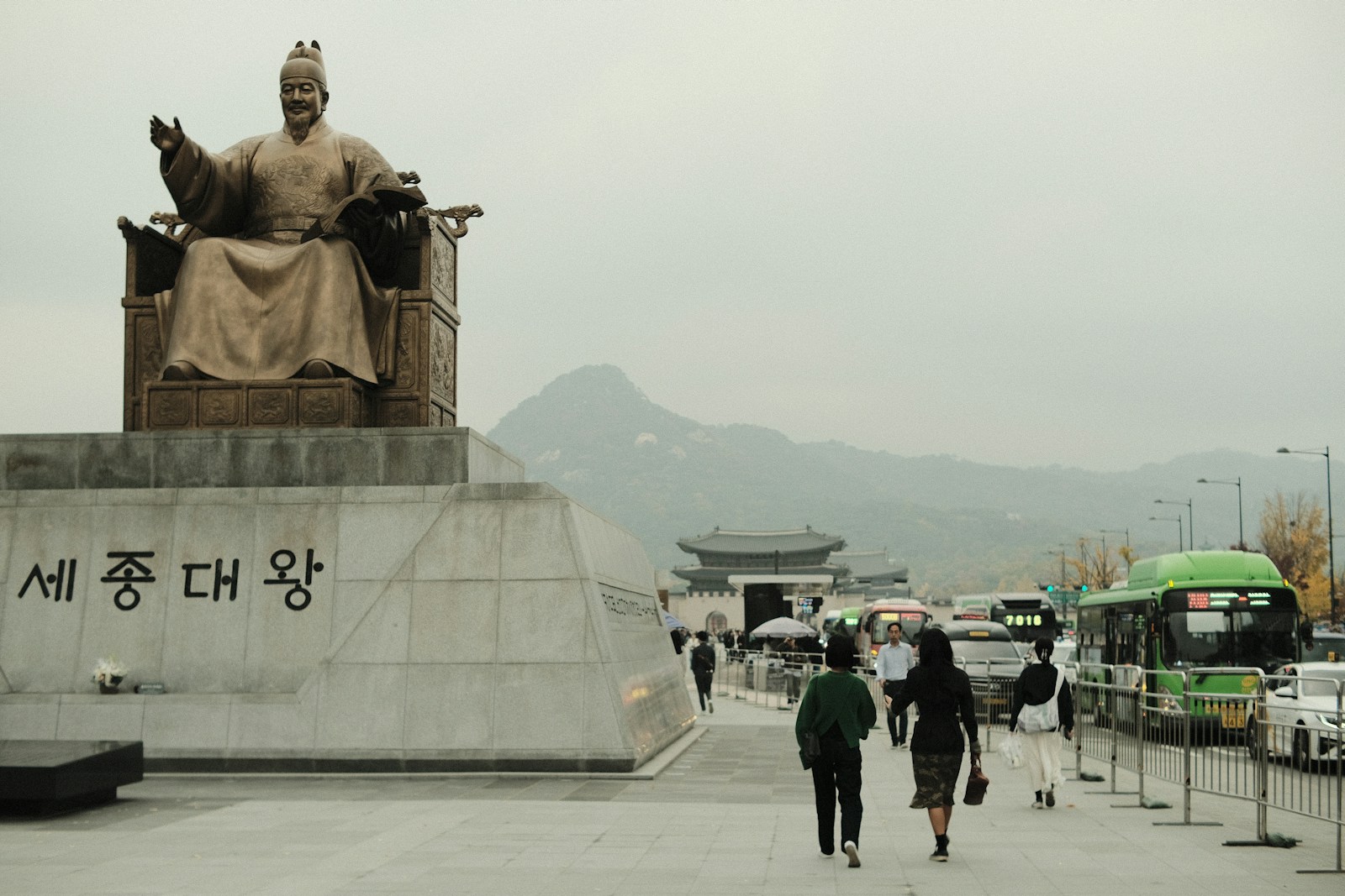 a group of people walking down a sidewalk next to a statue