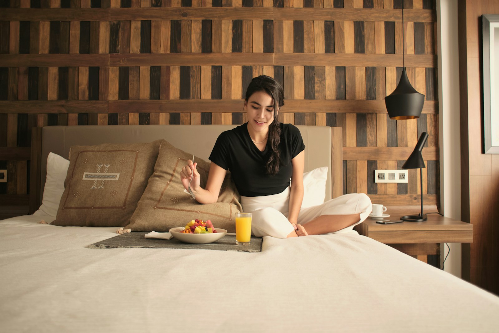 A woman sitting on a bed in a hotel room