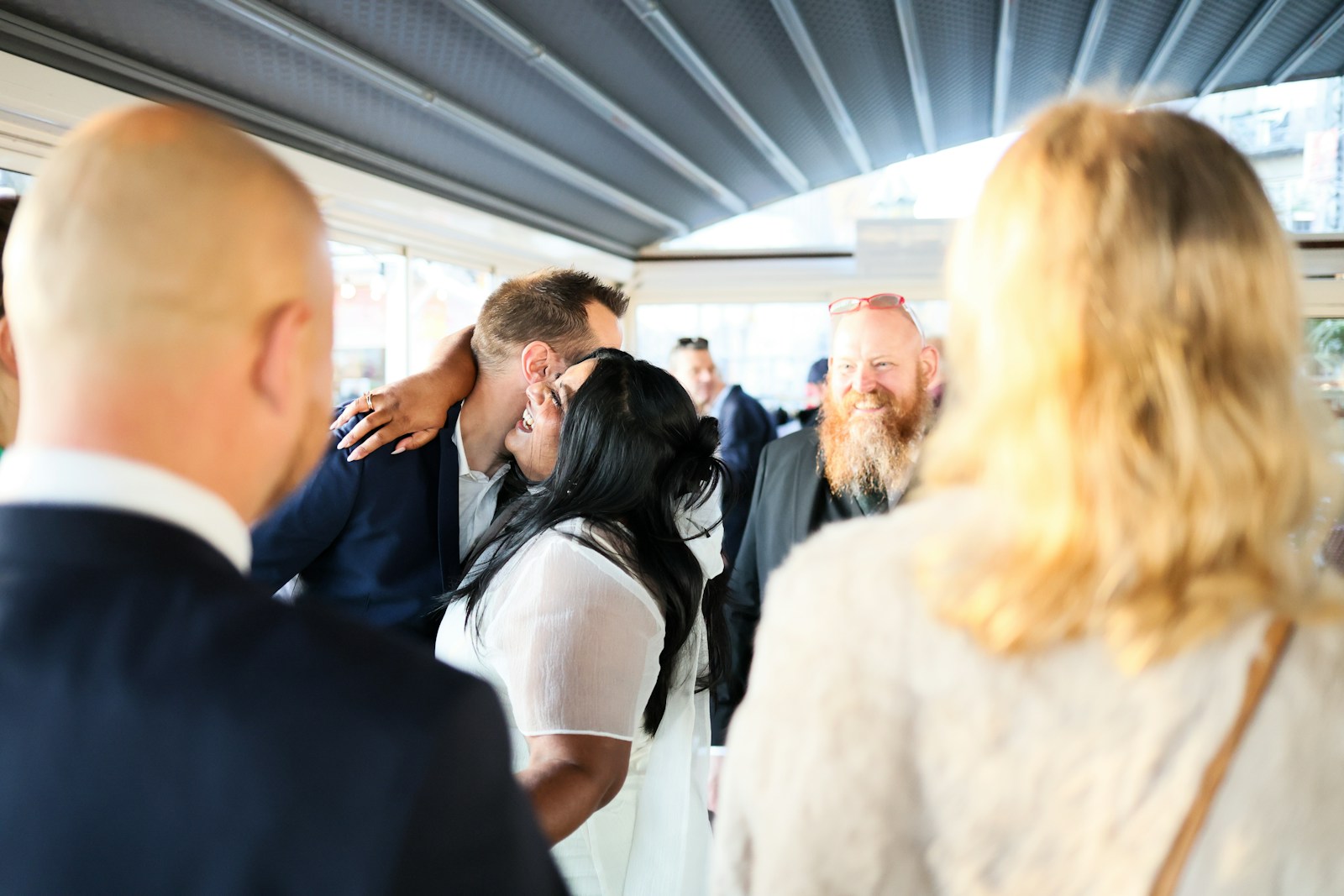 Couple embracing at an outdoor event with guests