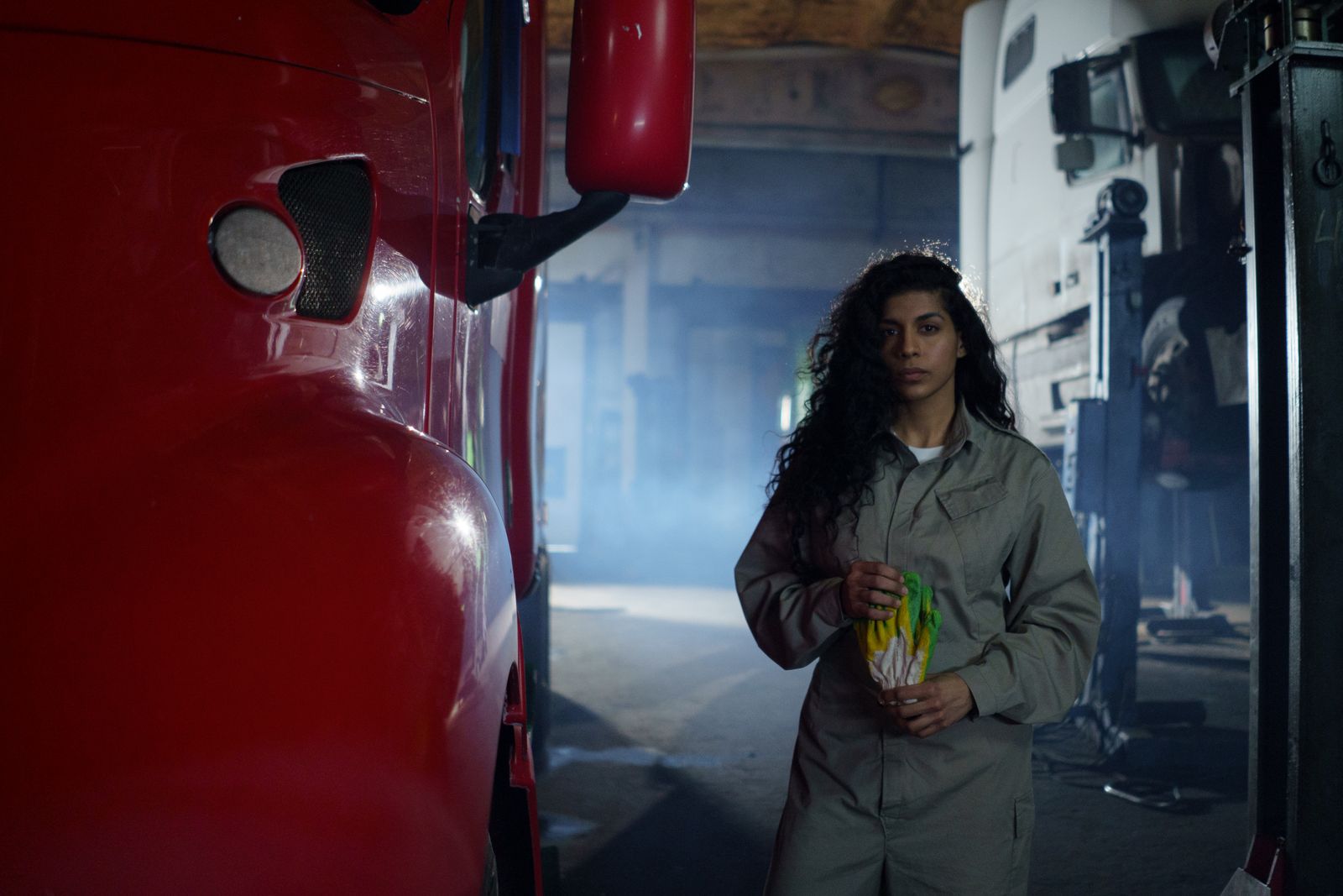 Portrait of a female mechanic in a garage holding tools, showcasing empowerment and skill in automotive work.