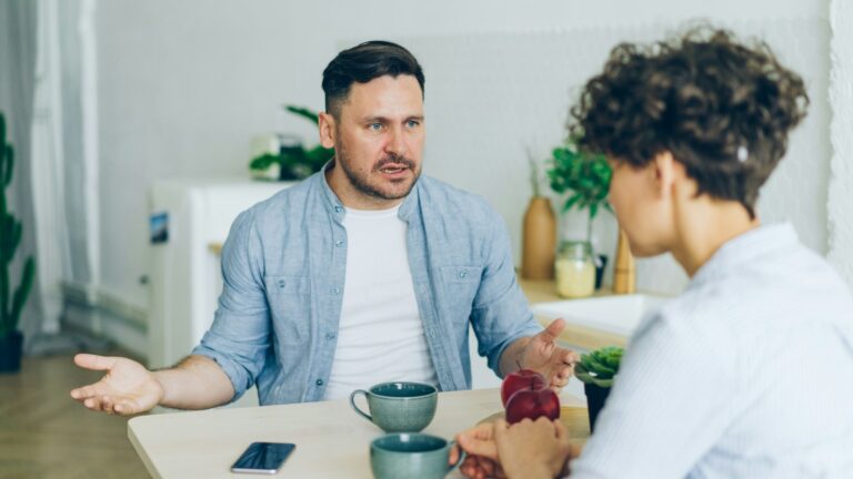 A man and woman arguing at a kitchen table. Photo by Vitaly Gariev on Unsplash.