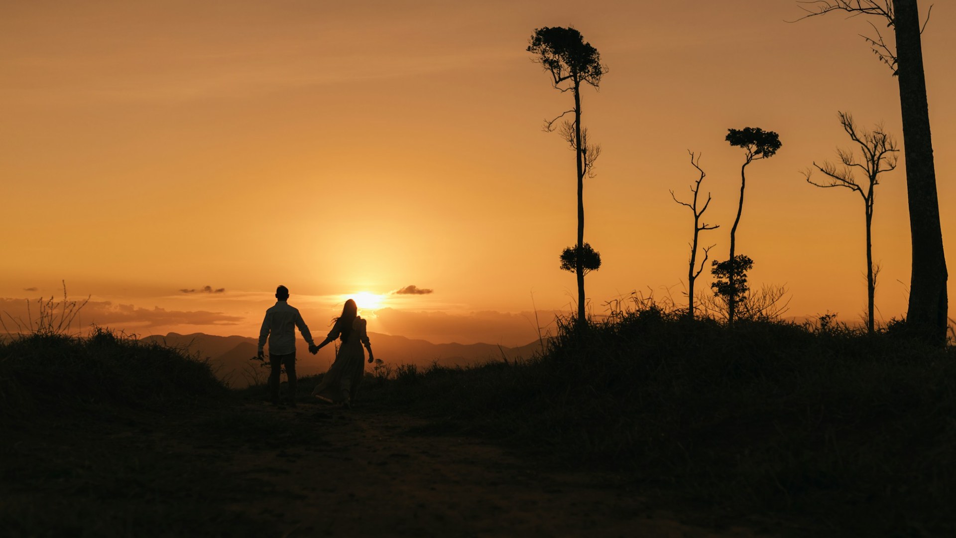A couple holding hands as the sun sets. Photo by J. Balla Photography on Unsplash.