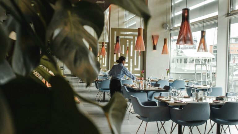 A woman at a dining table inside a restaurant. Photo by Louis Hansel on Unsplash.