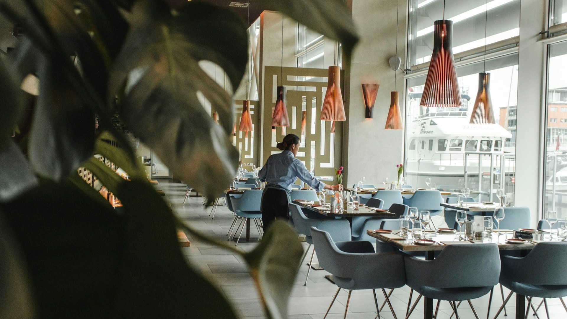 A woman at a dining table inside a restaurant. Photo by Louis Hansel on Unsplash.