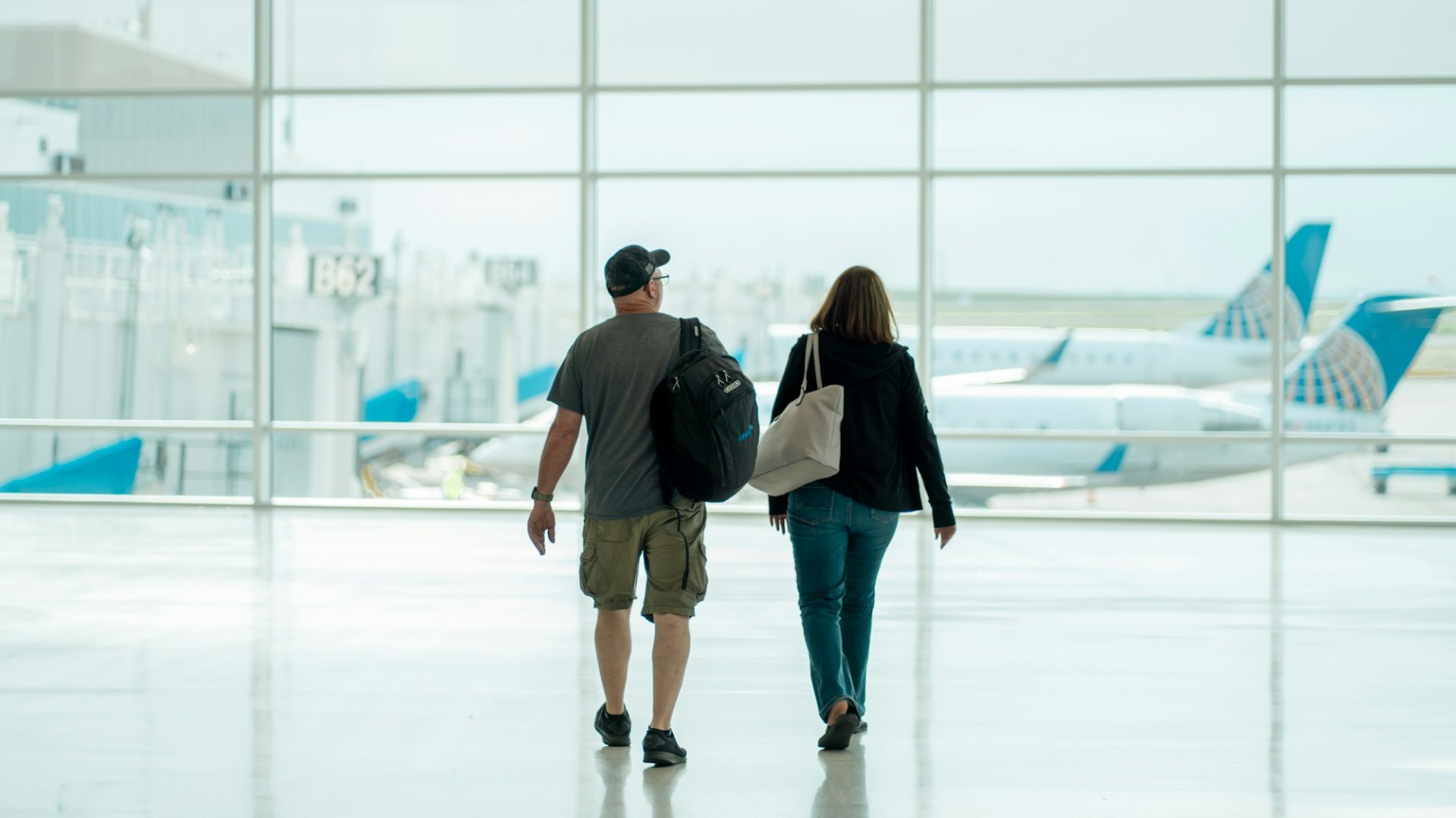 A man and a woman walking through an airport. Photo by Cameron Cox on Unsplash.