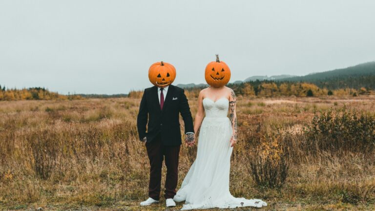 A couple wearing pumpkin heads in a field. Photo by Jonathan Cooper on Unsplash.