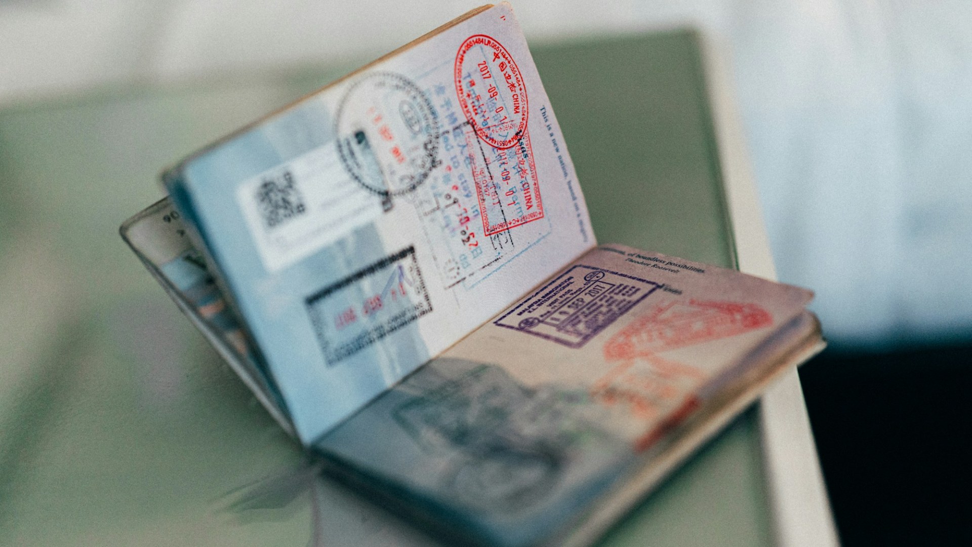 An open passport with many colourful ink stamps. Photo by Kit (formerly ConvertKit) on Unsplash.