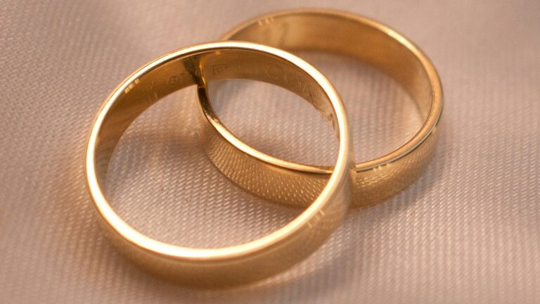 Unsplash photo by Mariano Rivas showing two linked gold wedding bands on cream fabric