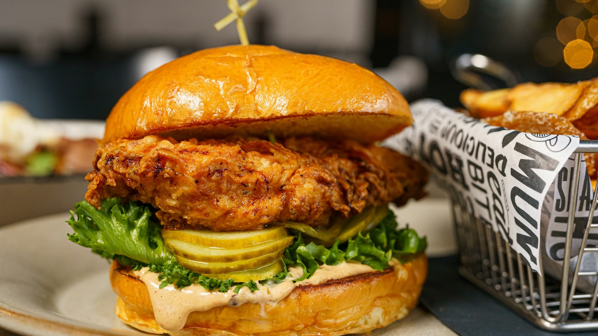 Unsplash photo by Hybrid Storytellers showing a chicken sandwich on a plate next to a basket of fries