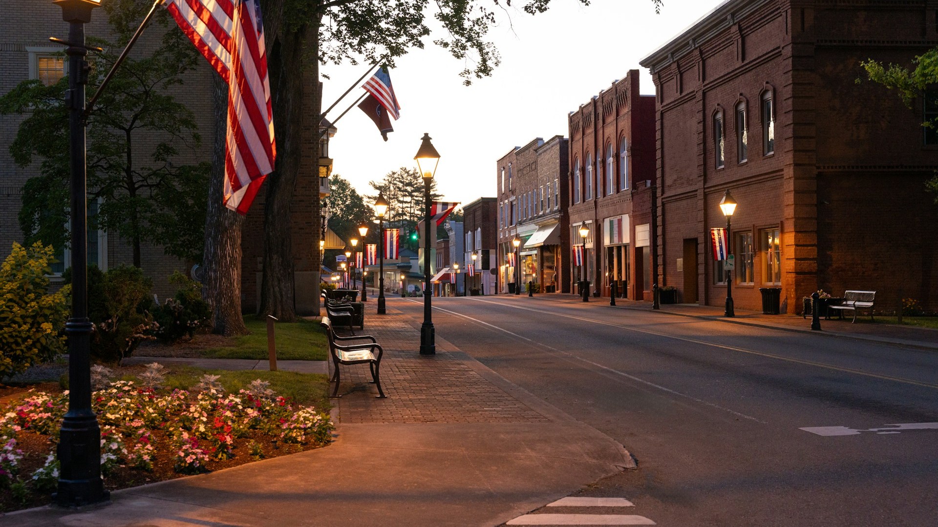 Unsplash photo by Land O'Lakes, Inc. showing a small town street at dusk lined with American flags