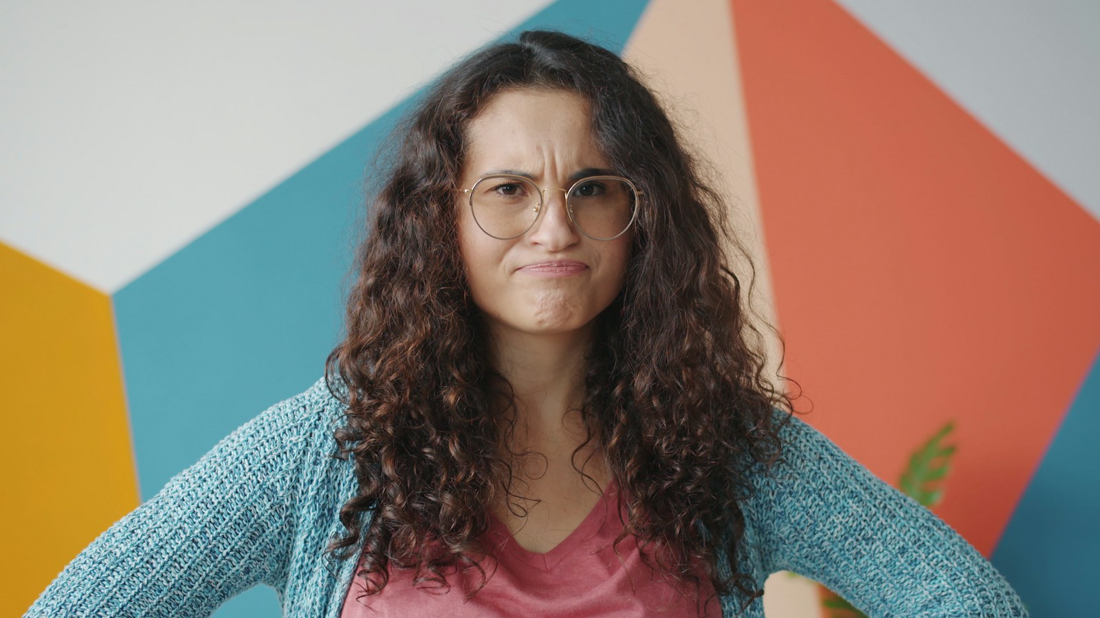 Woman with curly hair and glasses looks annoyed