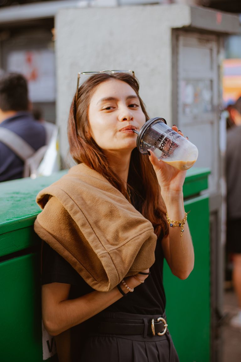 Portrait of a young woman sipping iced coffee outdoors, radiating a relaxed and cool vibe.