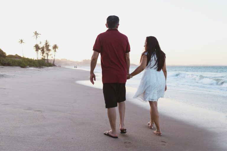 a man and a woman walking on a beach holding hands